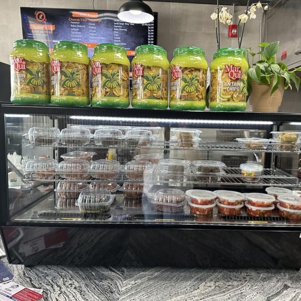 A display case at Shawarma Shack with Mar Qui plantain chips, pre-packaged food, and a menu.